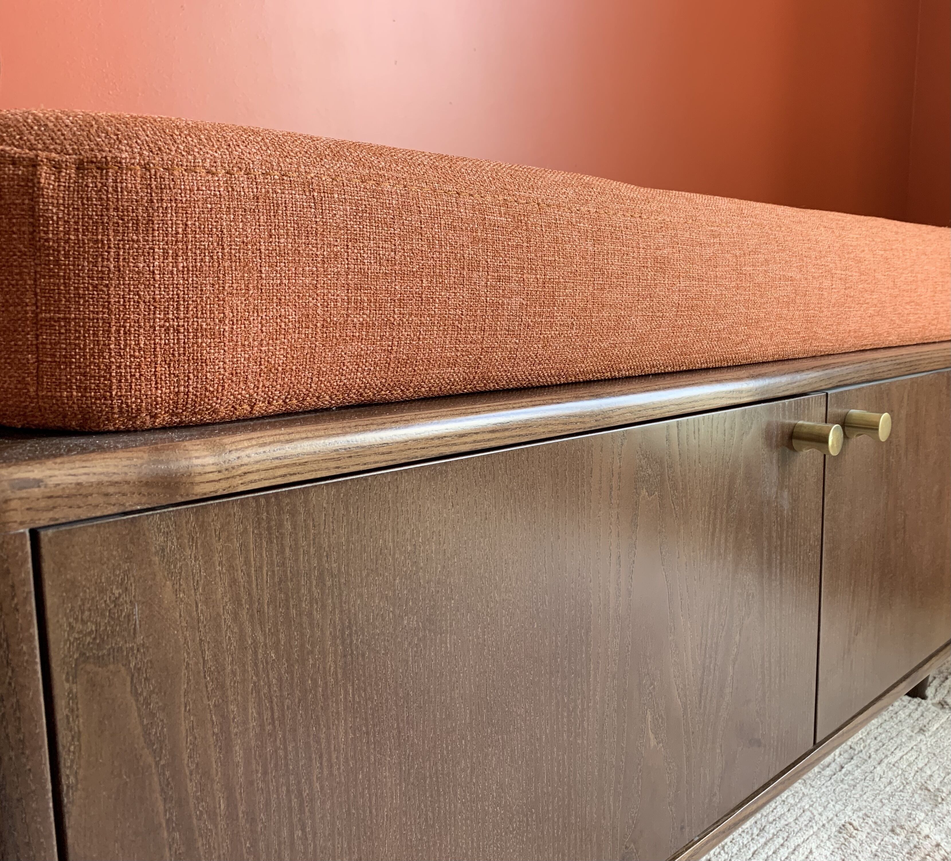 A wooden cabinet with a textured fabric top.