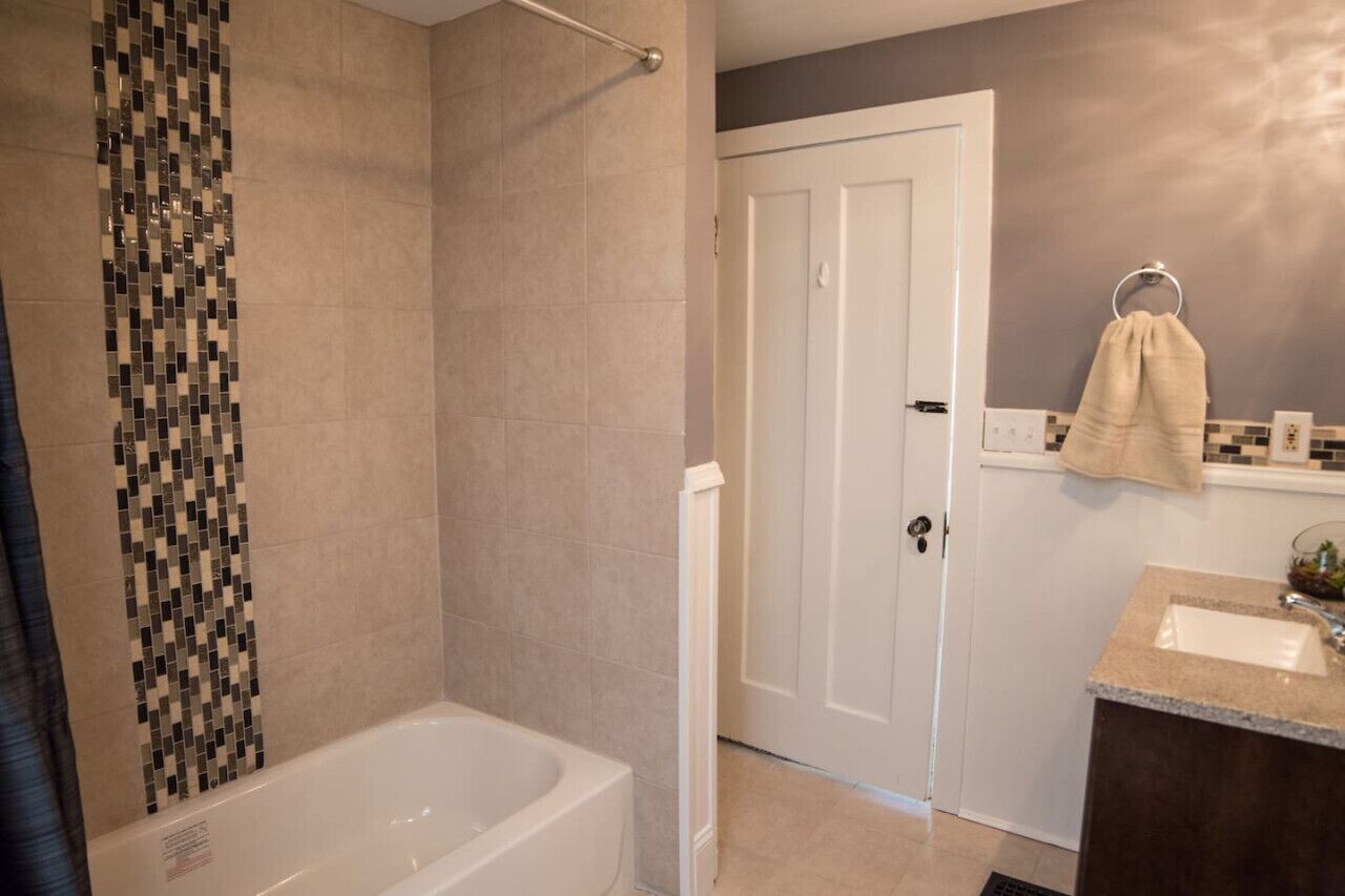 A bathroom with a bathtub, a shower area, a sink, and a towel rack.