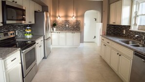 Eine moderne Küche mit Edelstahlgeräten, weißen Schränken und einer gefliesten Spritzschutzwand.