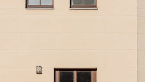 A beige building with a brown double door and a small window above it. - Design Apartments - "Kutscherhaus" (Potsdam)