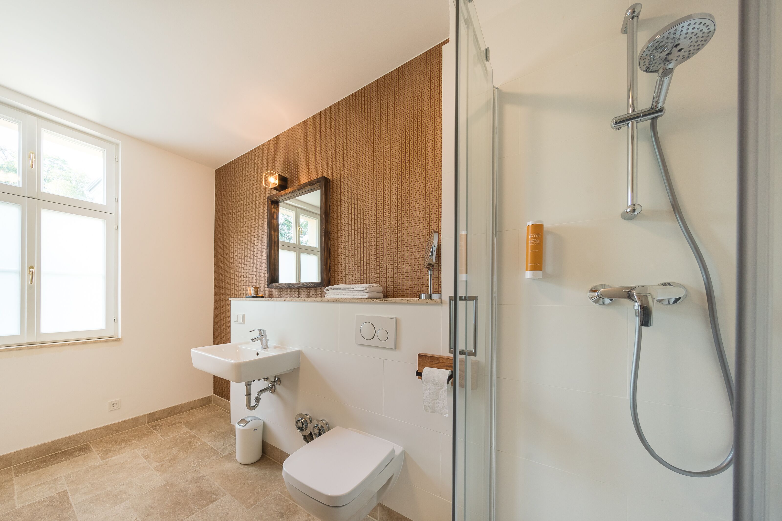 A bathroom with a glass-enclosed shower, a sink, and a toilet.