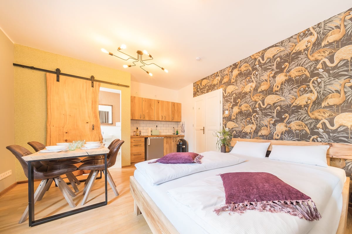 Ein Schlafzimmer mit Bett, einem Esstisch mit Stühlen, einer Küchenzeile und einem Badezimmer.