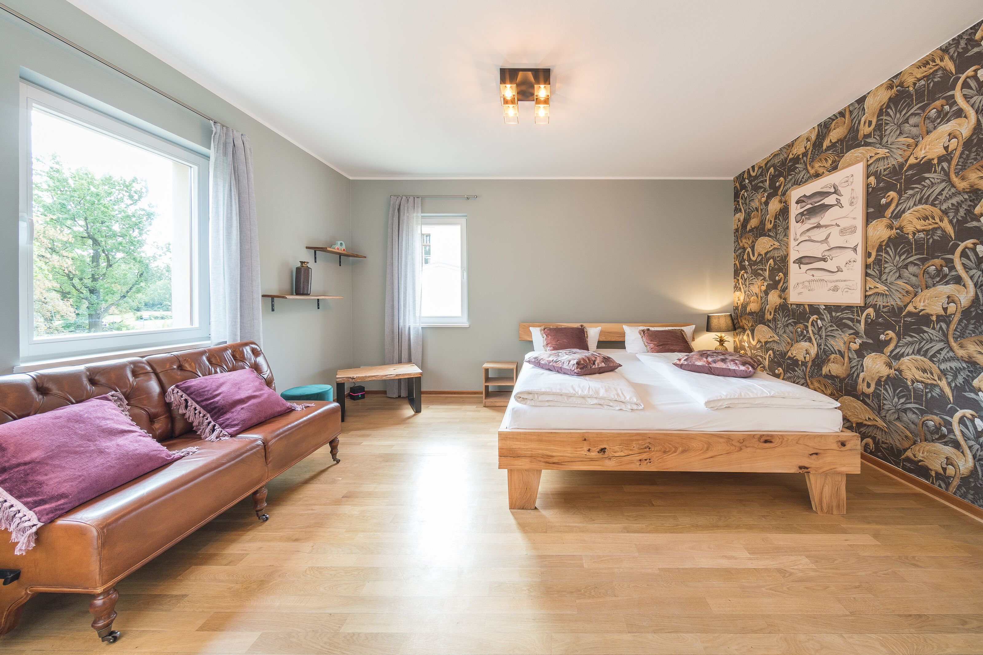Un dormitorio con una cama de madera, un sofá de cuero y un ventanal grande.