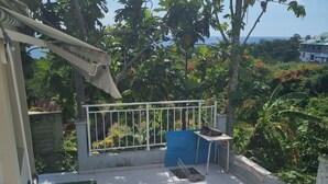 Un patio piastrellato con ringhiera bianca, una panca blu e un tavolino.