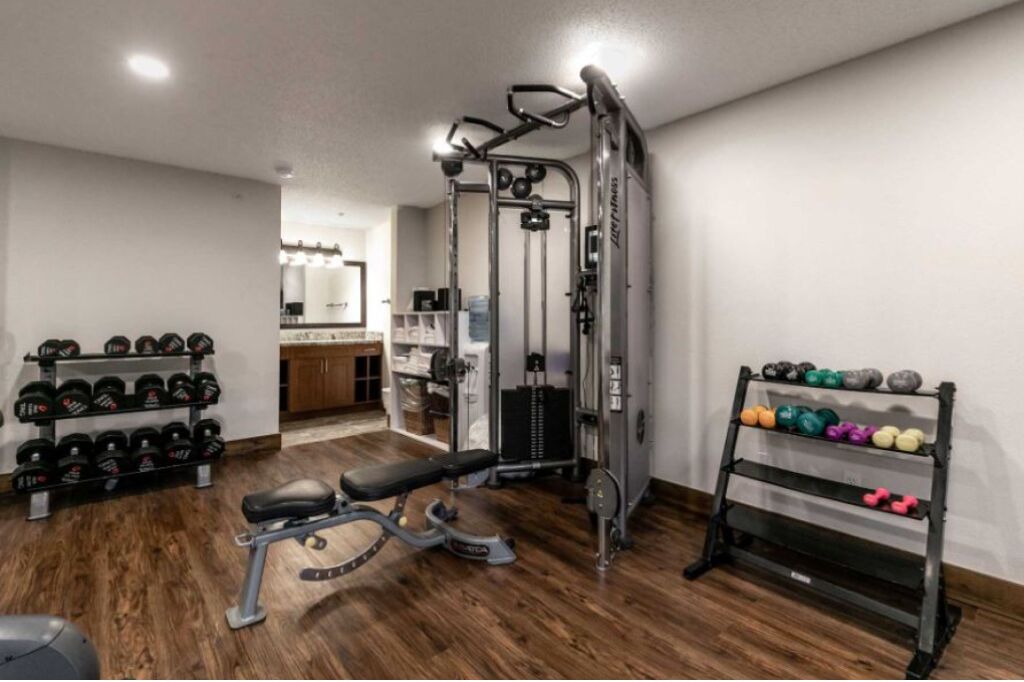 A home gym with a bench press, dumbbells, and a squat rack.