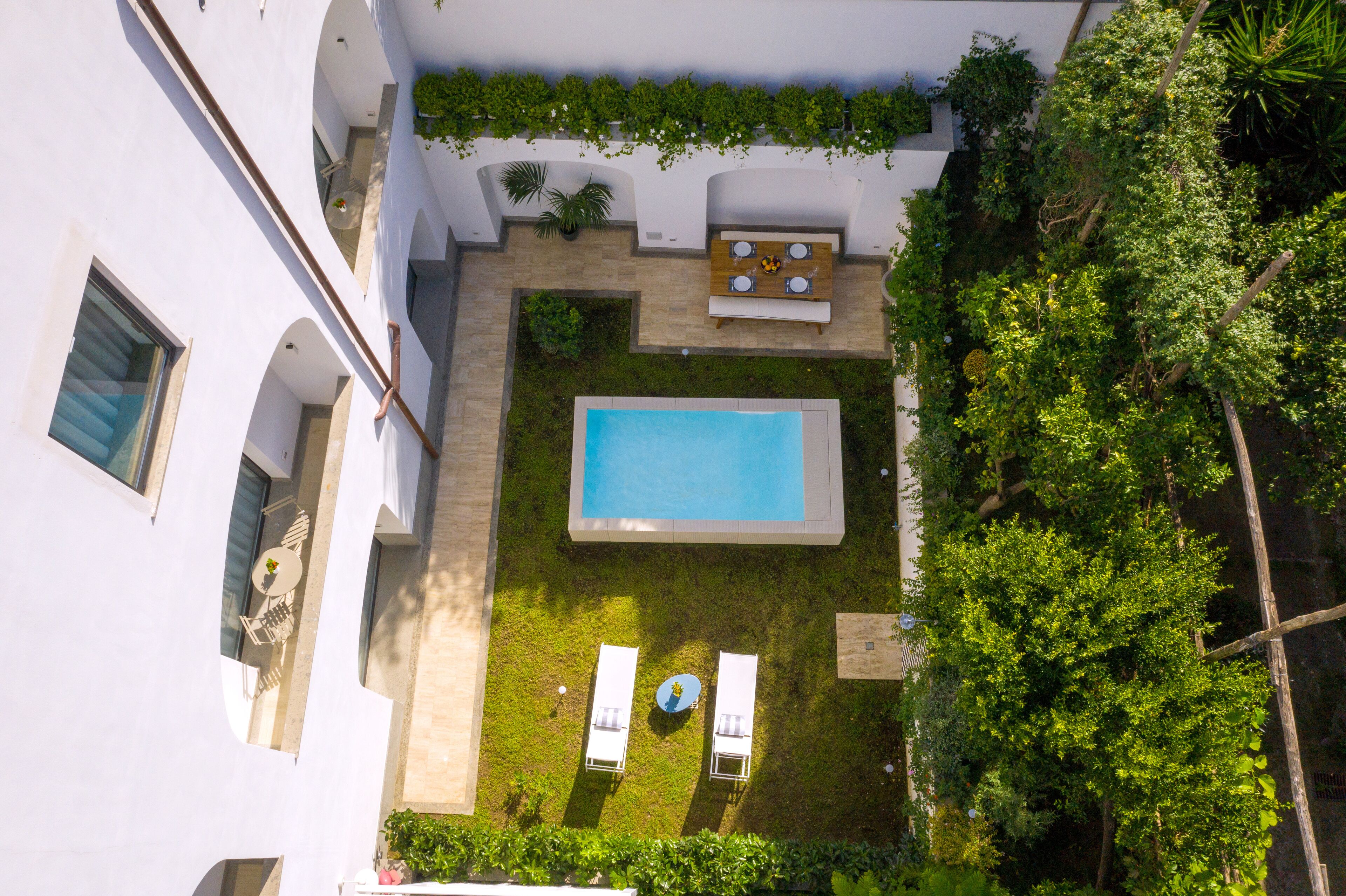 Vista aérea de un patio con piscina, sillas de descanso y una mesa con sillas.