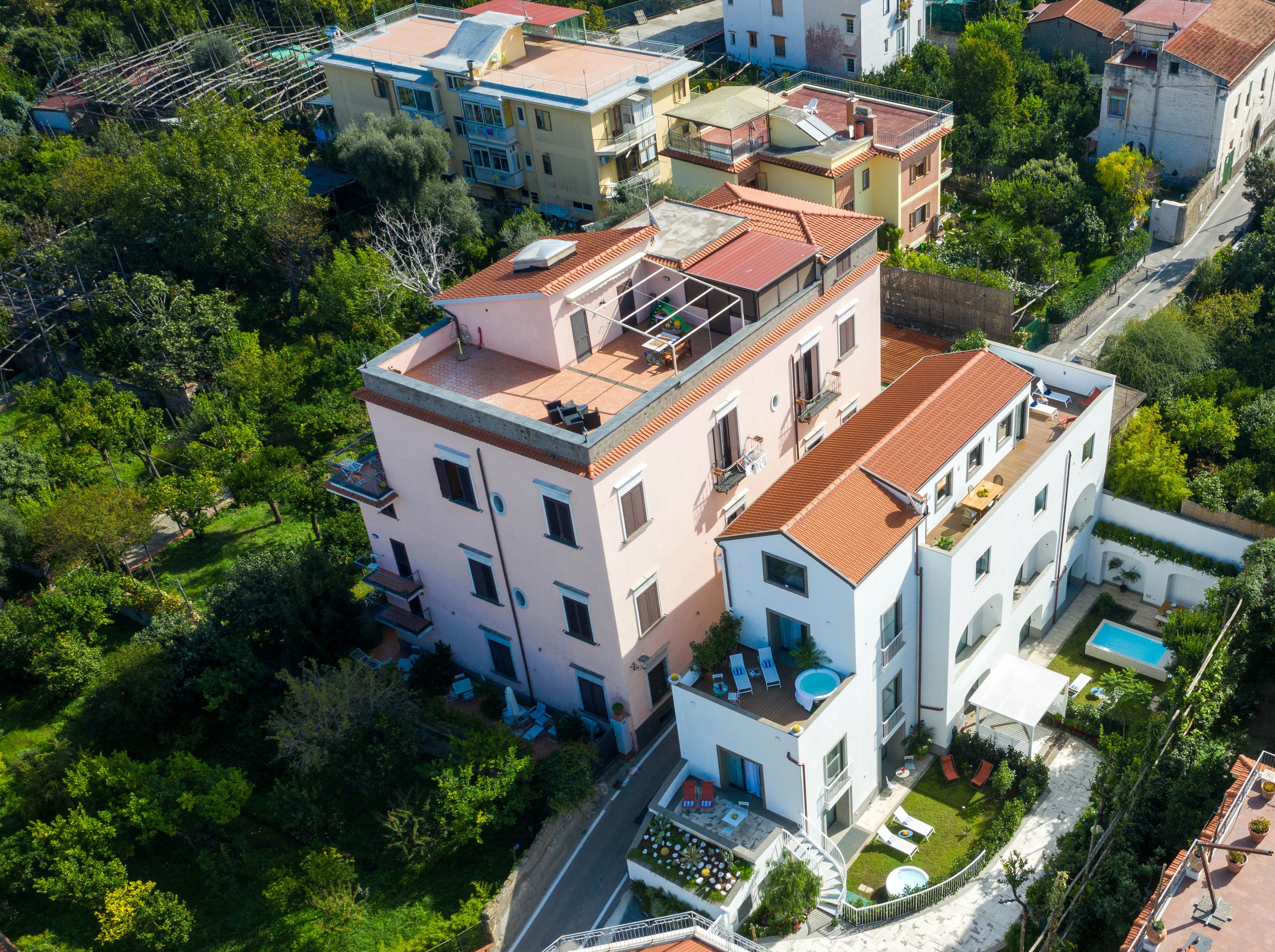 Vista aérea de un edificio residencial con varios pisos, balcones y una piscina.
