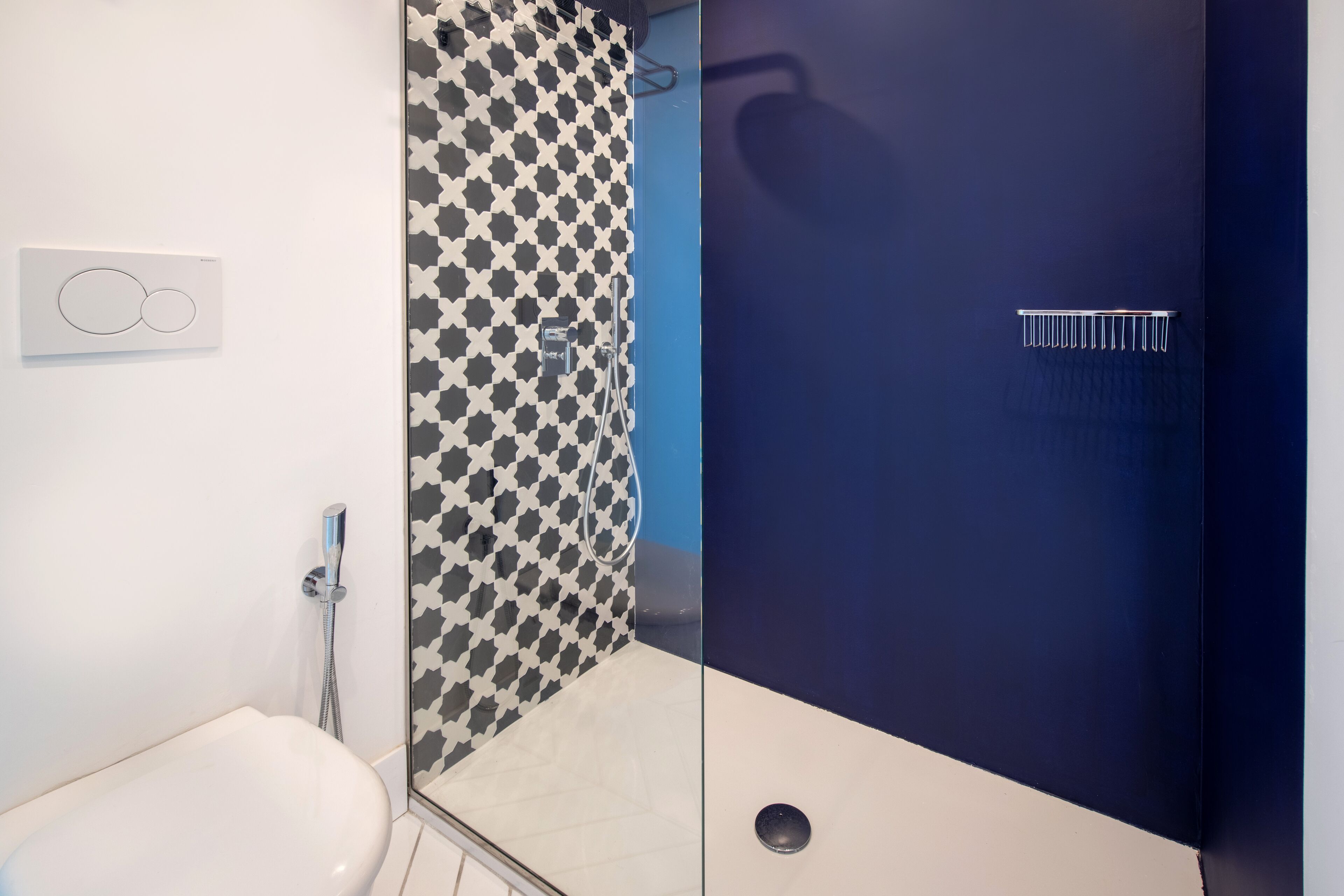 A modern bathroom with a white toilet, a shower with a black and white checkered shower curtain, and a blue accent wall.
