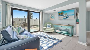 Un salon moderne avec un canapĂ©, une console de couleur turquoise et une grande fenĂȘtre donnant sur une terrasse.
