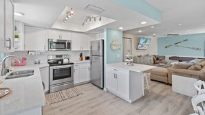 Une cuisine moderne avec des armoires blanches, des appareils en acier inoxydable et un mur dâaccent bleu clair.