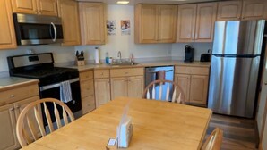 Uma cozinha moderna com armários de madeira, eletrodomésticos de aço inoxidável e uma mesa de jantar de madeira.