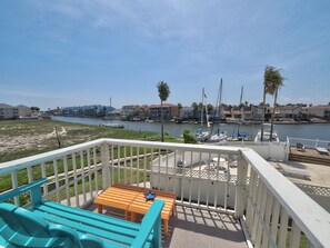A deck with a wooden table and chairs, overlooking a marina with boats and a river. - Canal View❤️fishing Dock❤️Close to Beach❤️Waterfront (Corpus Christi)