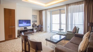 Habitación de hotel con televisor grande, sofá, mesita de centro, escritorio y silla.