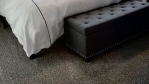 Un dormitorio con cama, ventilador de techo, mesita de noche y ventana con cortinas.