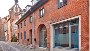 A red brick building with large windows and a cobblestone street.