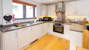 Una cocina moderna con armarios blancos, una campana extractora de acero inoxidable, un microondas y un lavavajillas.