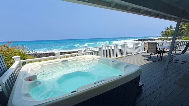 Een hottub op een houten terras met uitzicht op zee.