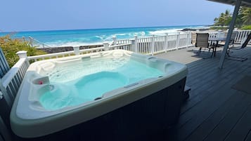 Un bain à remous sur une terrasse en bois, avec vue sur l’océan.