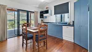 Een moderne keuken met blauwe kastjes, een houten eettafel en uitzicht op de omgeving.