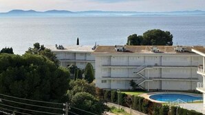 Un hôtel situé sur la côte, doté d’une piscine, offrant une vue sur la mer et un panorama montagneux.