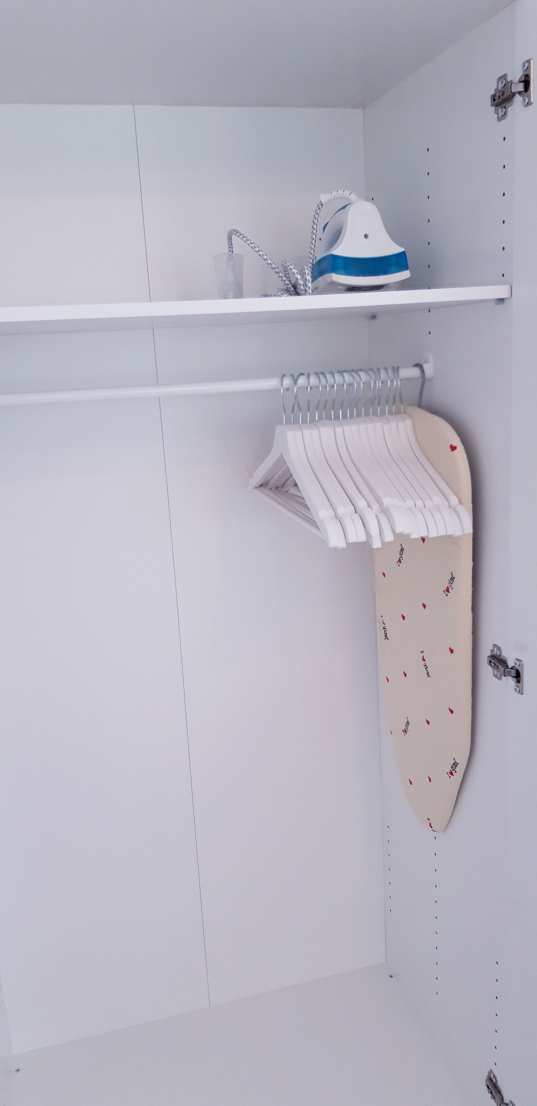 Ein weißer Kleiderschrank mit Kleiderstange und Ablagefläche.