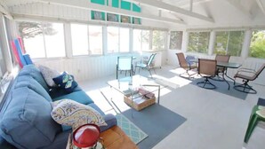 A spacious living area with a blue sofa, glass coffee table, and a dining table with chairs.
