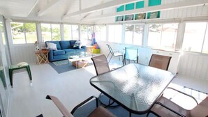 A covered patio area with a glass table and chairs, a blue sofa, and a small coffee table.