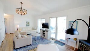 A modern living room with a white sofa, a coffee table, a TV, and a fireplace.