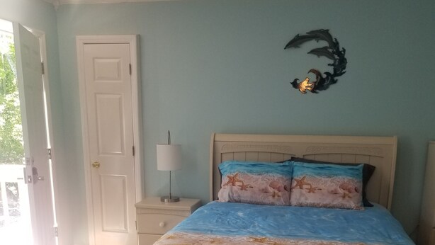 Une chambre à coucher avec un lit, une table de chevet, une lampe et une porte.