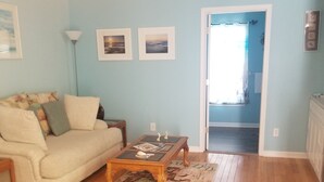 Un salon avec un canapé beige, une table basse en bois et un tapis à motifs.