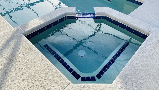 Une piscine dont le revêtement est constitué de carreaux disposés selon un motif géométrique, avec un élément circulaire central.