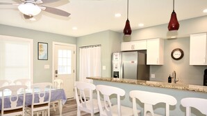 A modern kitchen with white cabinets, a stainless steel refrigerator, and a granite countertop. - Pet Friendly Downtown Rehoboth Beach House (Rehoboth Beach)