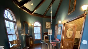 A spacious room with high ceilings, wooden beams, and large windows.