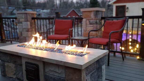 A fire feature with two red chairs and a stone wall.
