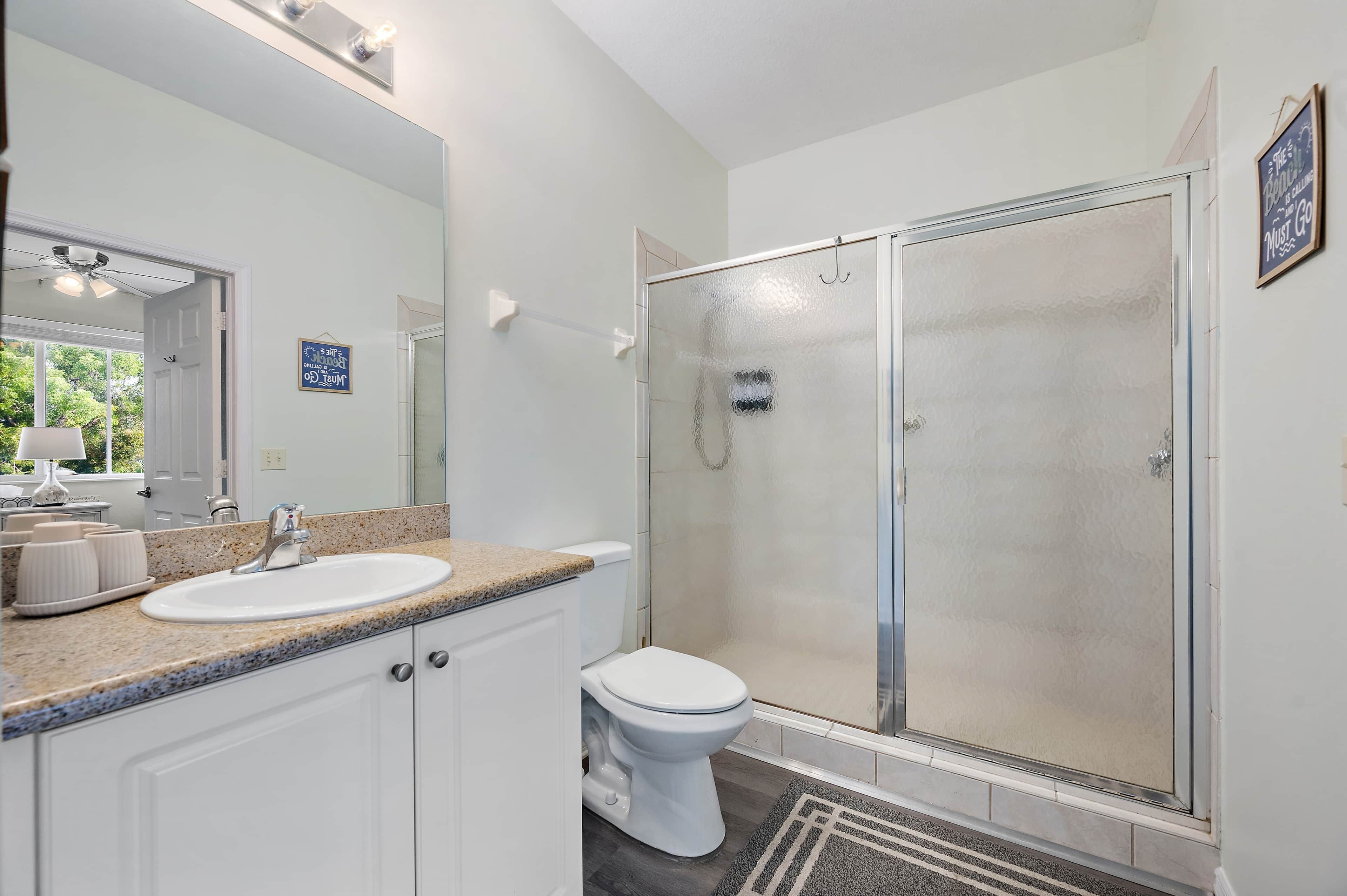 Een badkamer met een witte wastafel, toilet en douchecabine.