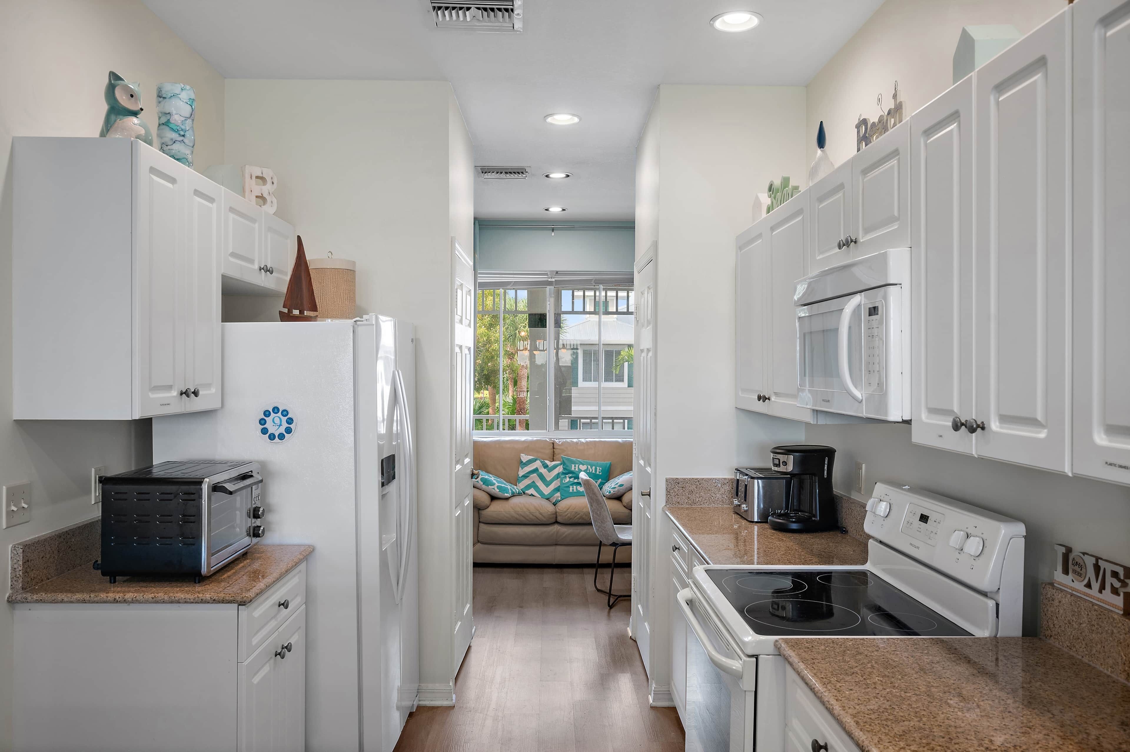A modern kitchen with white cabinets, a toaster, a microwave, and a stove.