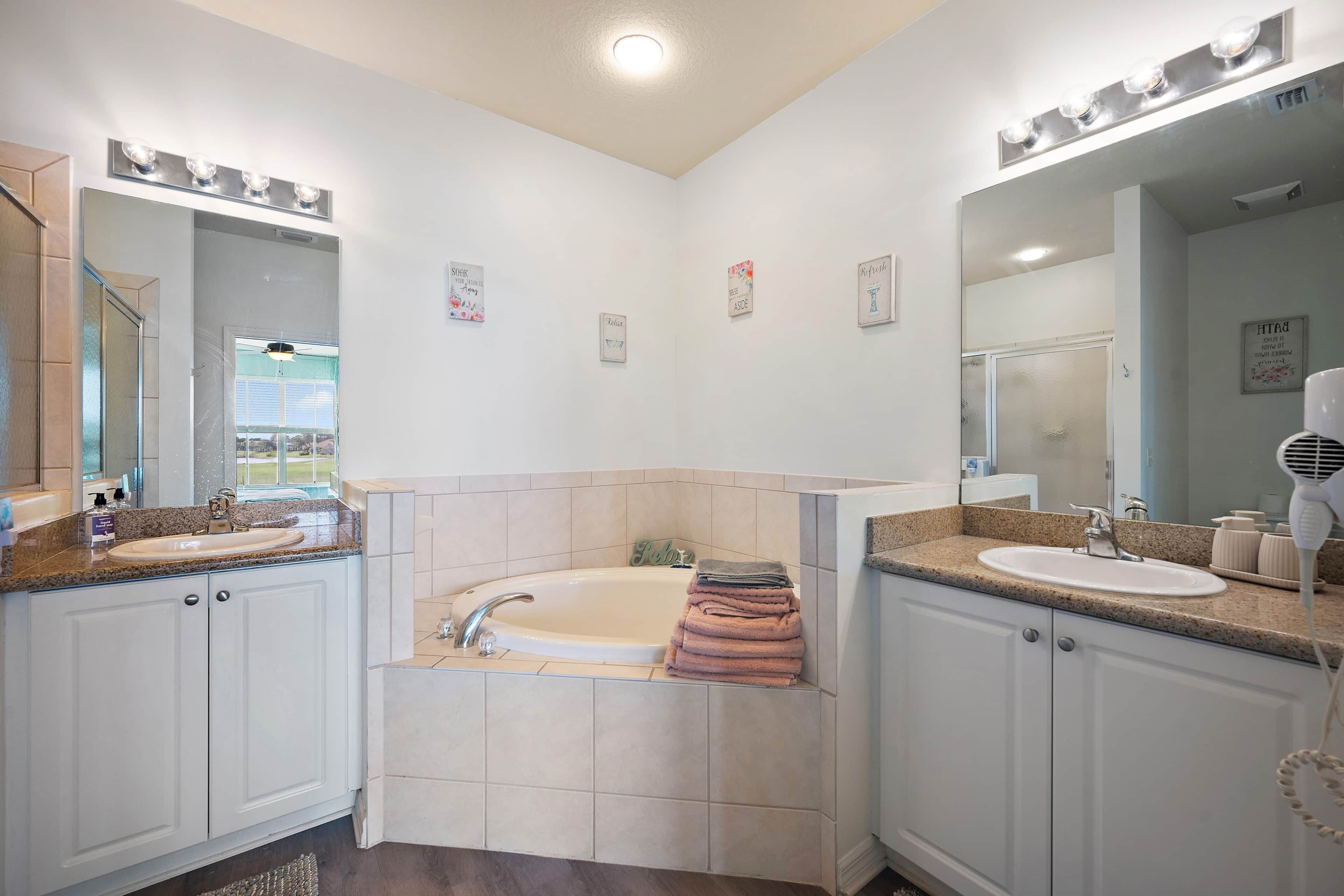 A bathroom with two sinks, a bathtub, and a large mirror.