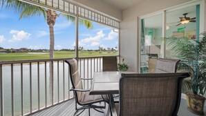 Ein Balkon mit Blick auf einen Golfplatz und Palmen, ausgestattet mit einem Tisch und Stühlen.