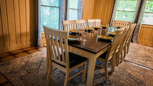 A dining area with a wooden table set for six, surrounded by six wooden chairs.