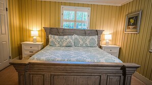 A traditional bed with a wooden headboard, two bedside tables with lamps, and a window with blinds.