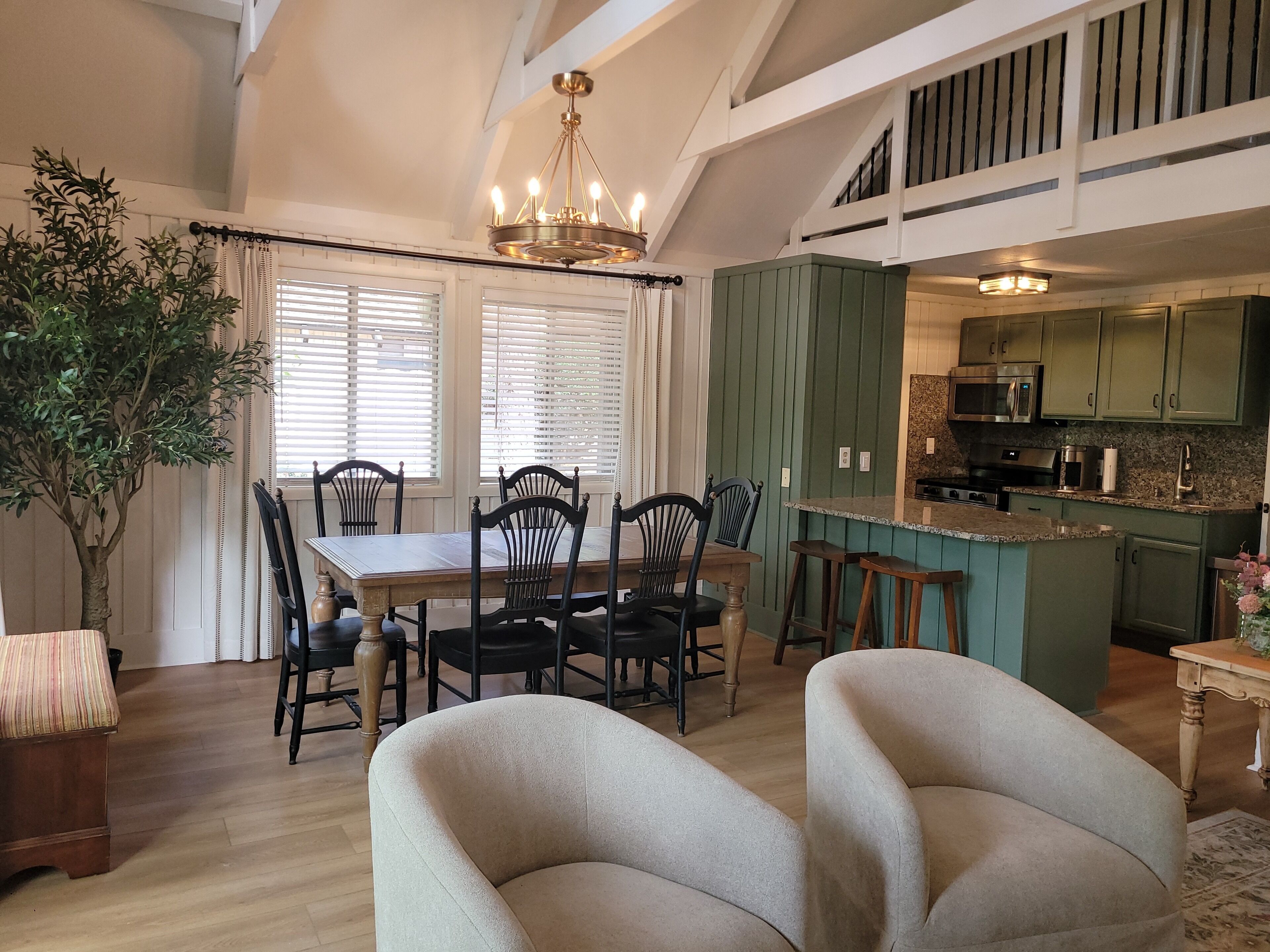 A dining area with a table and chairs, a chandelier, and a view of the kitchen.