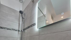 A bathroom with a shower, a sink, and a mirror.
