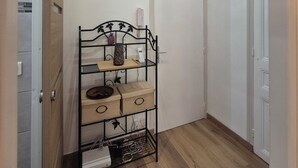 A room with a wooden floor, a metal shelf unit with drawers, a white door, and a white wall.