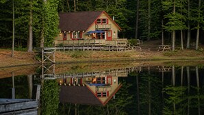Eine Hütte mit Terrasse, einem Steg und einem Spiegelbild im Wasser.