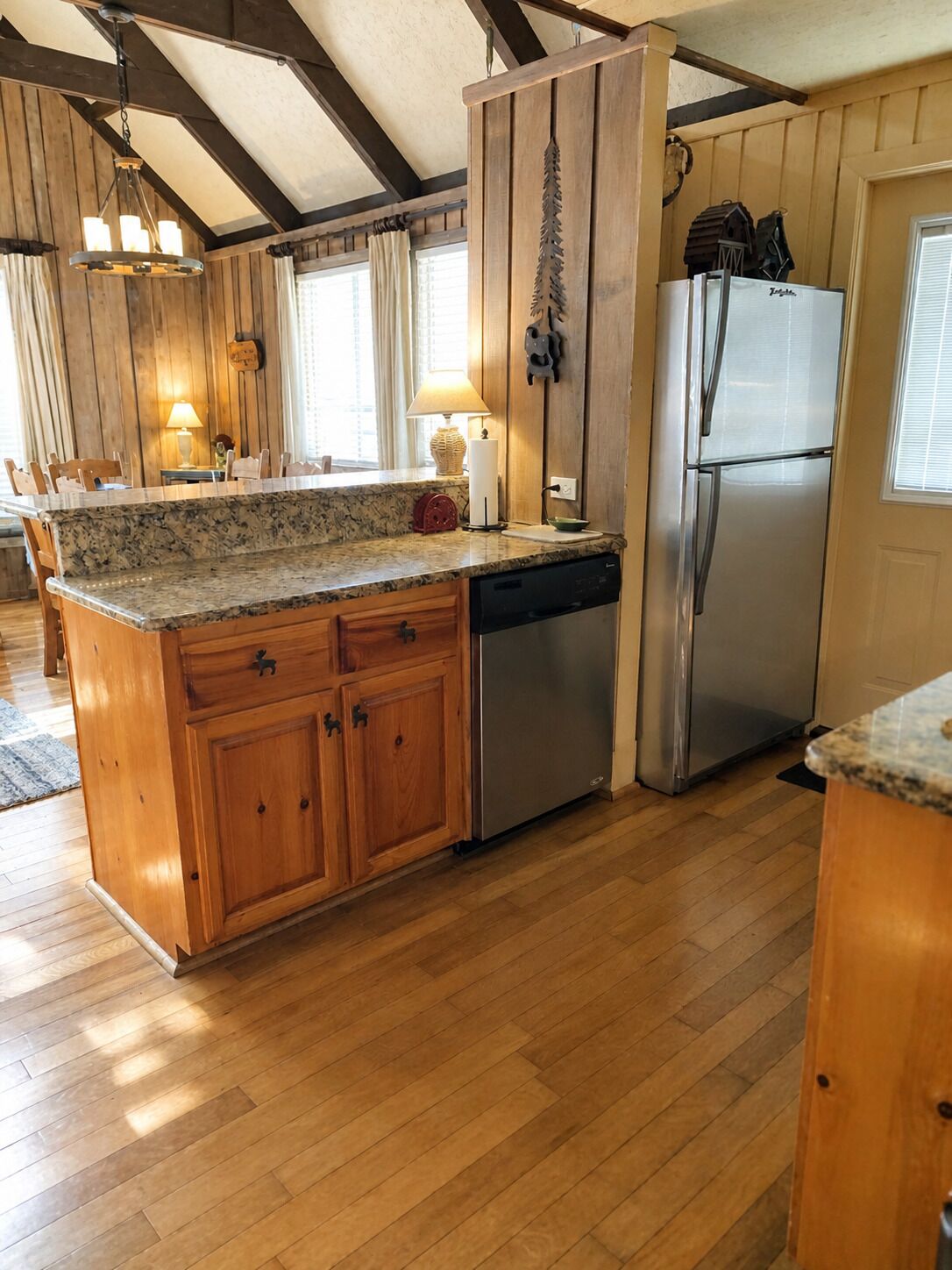 A kitchen with wooden cabinets, a stainless steel refrigerator, and a granite countertop.