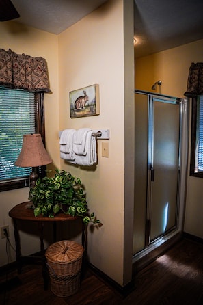 Bathroom features a glass shower enclosure, a wall-mounted towel rack, and a potted plant.