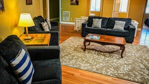 A living room with a sofa, armchair, coffee table, and a lamp.