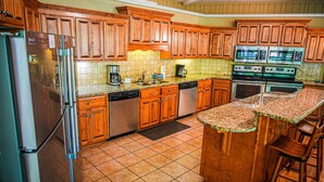 A kitchen with wooden cabinets, a stainless steel refrigerator, a dishwasher, a coffee maker, and a stove.
