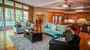 A spacious living room with a large window, a fireplace, and a kitchen area.