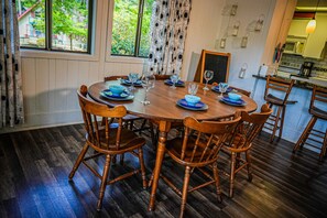 Enjoy meals in this dining area with a round table for four, surrounded by matching chairs and a view of lush greenery.